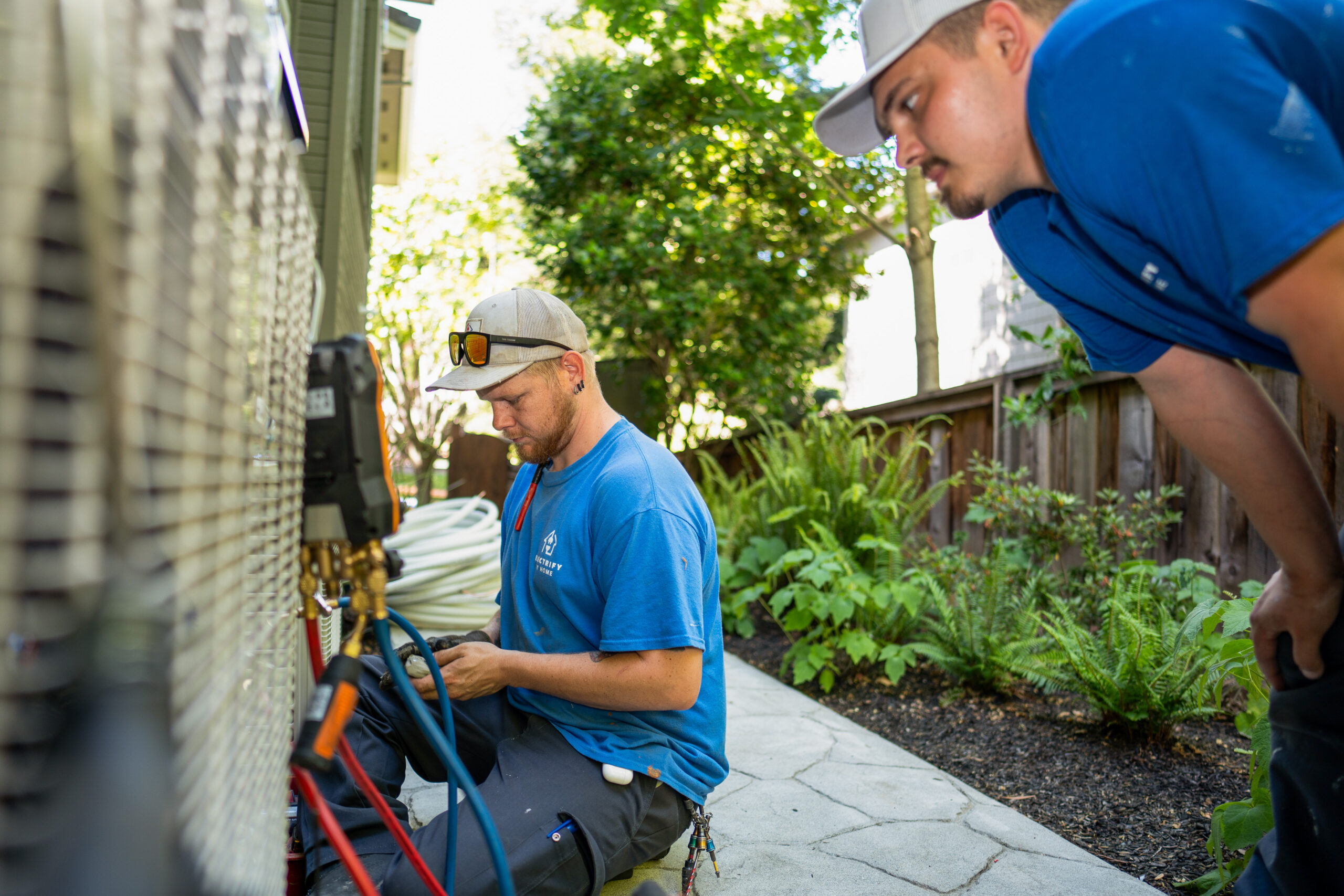two contractors work on a heat pump