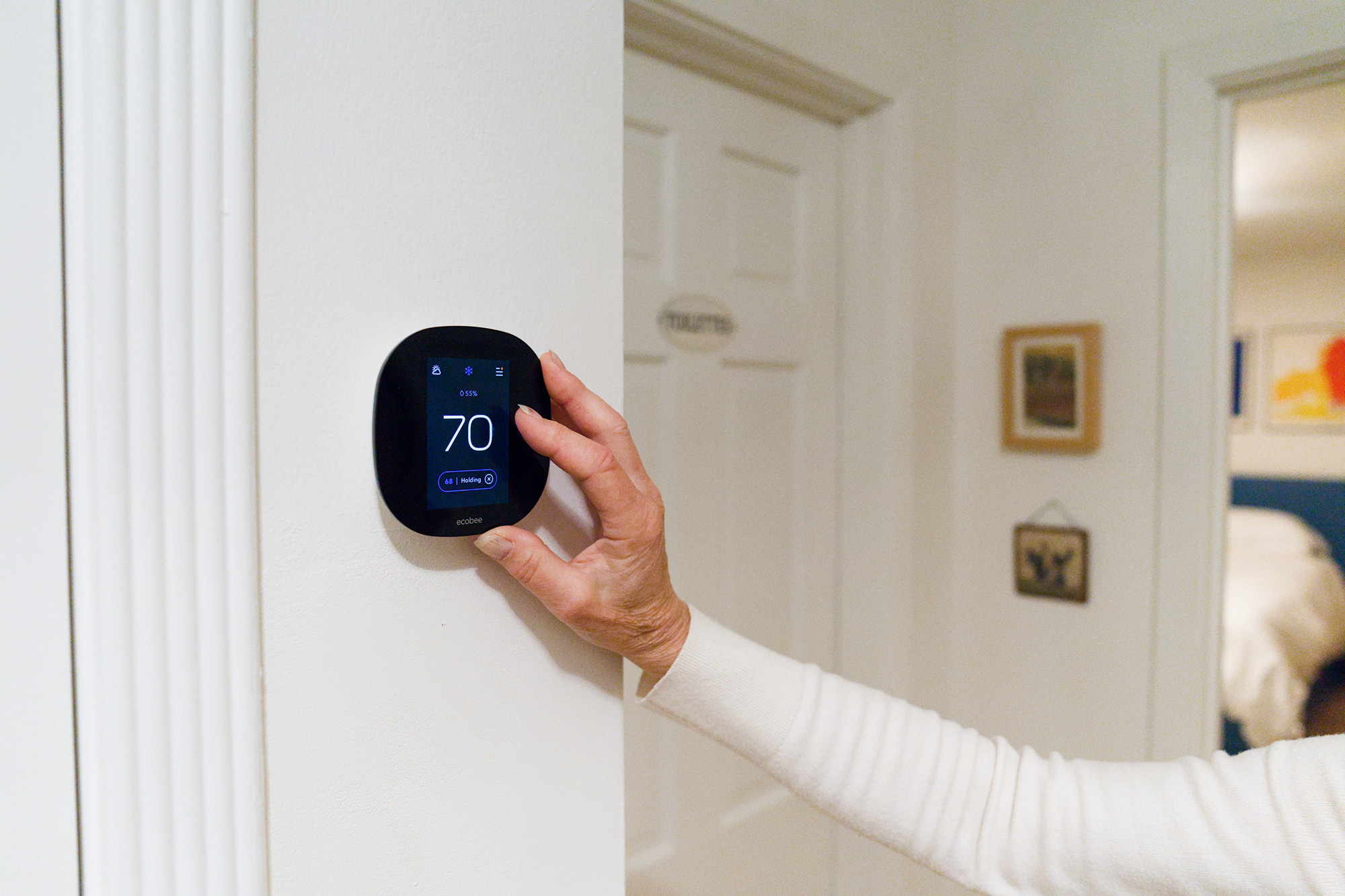 Photo of someone adjusting a digital thermostat